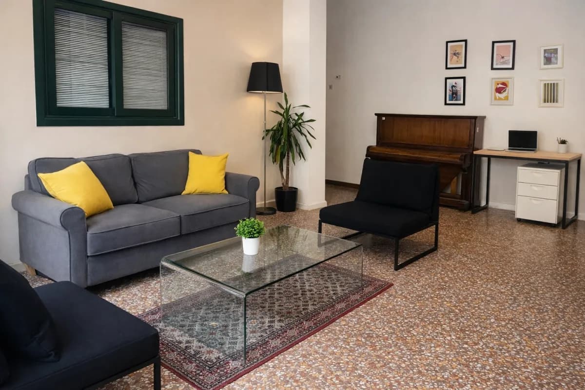 Area relax coworking Voler.ai Verona — salottino con divani, pianoforte e pavimento in terrazzo veneziano